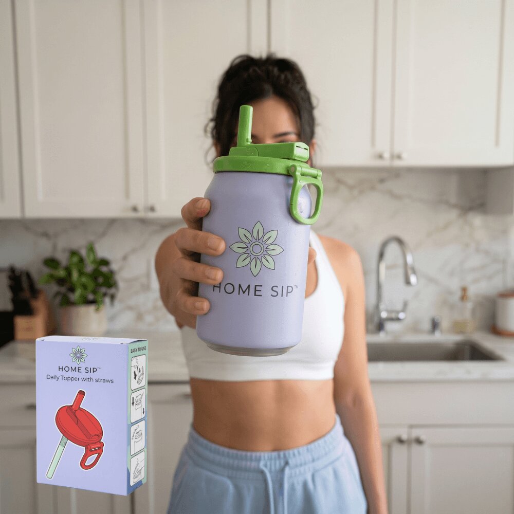 A woman in a kitchen holds a large lavender Home Sip tumbler with a green lid and straw. The image includes an inset of the product packaging box in the lower left corner.